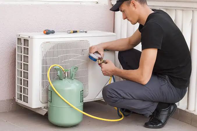 Technician checking an outdoor air conditioner with a pressure gauge