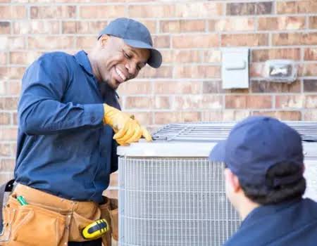 Two HVAC technicians working beside an outdoor condenser