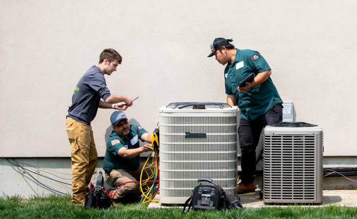 HVAC technicians inspecting residential outdoor heating and cooling equipment