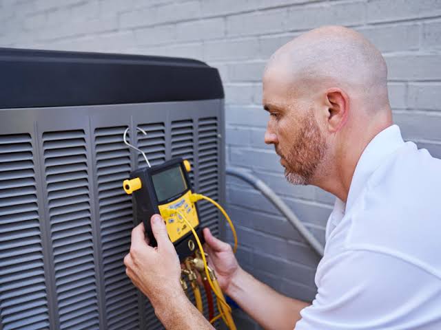 Technician testing an outdoor HVAC unit with an electrical meter